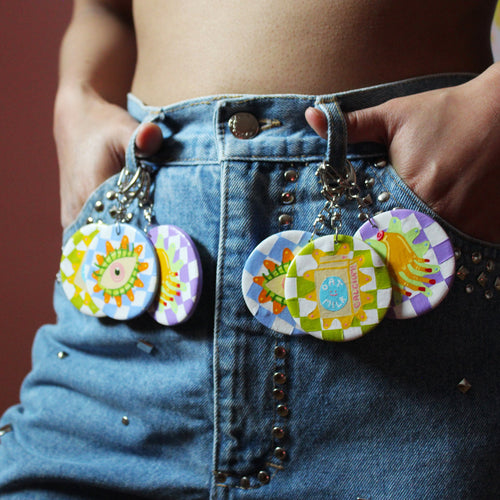 Close up of woman wearing silver studded blue jeans with keyrings with round pendants hanging on belt hoops